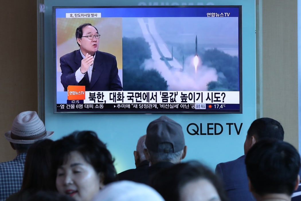People watch a television news programme, showing file footage of a North Korean missile launch, at a railway station in Seoul on May 14, 2017.