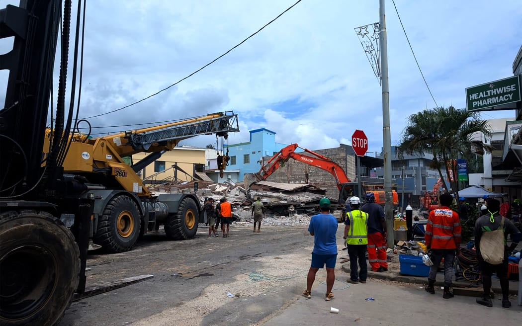 Rescue workers are seen at the site of a collapsed building after an earthquake struck Port Vila, the capital city of Vanuatu, on December 18, 2024. - Rescue teams dug for survivors trapped in crumpled buildings in the Pacific nation of Vanuatu on December 18 after a powerful earthquake killed at least 14 people, some of them buried in rubble and landslides. (Photo by STRINGER / AFP)