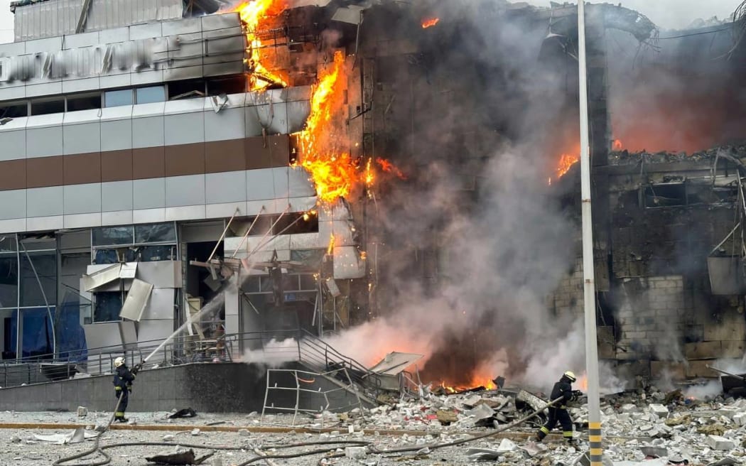 This handout photograph taken and released by Ukrainian Emergency Service on December 29, 2023, shows firefighters working in a burning building at a site following an attack in Dnipro, amid the Russian invasion of Ukraine. Russia launched drone and missile strikes across Ukraine on December 29, 2023, killing at least 18 people and wounding over a hundred in one of the most massive air attacks of the war. (Photo by Handout / UKRAINIAN EMERGENCY SERVICE / AFP) / RESTRICTED TO EDITORIAL USE - MANDATORY CREDIT "AFP PHOTO /HO/ UKRAINIAN EMERGENCY SERVICE " - NO MARKETING NO ADVERTISING CAMPAIGNS - DISTRIBUTED AS A SERVICE TO CLIENTS