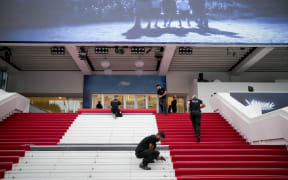 Festival workers lay the red carpet at the Palais des Festivals on opening day of the 77th international film festival, Cannes, southern France, Tuesday, May 14, 2024. The Cannes film festival runs from May 14 until May 25, 2024.