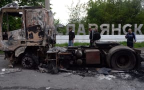 People walk past a burned truck near the eastern Ukranian city of Sloviansk.