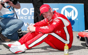 Scott McLaughlin who is exhausted sits on the ground in the winner's circle after winning the Grand Prix of St. Petersburg , 2022.