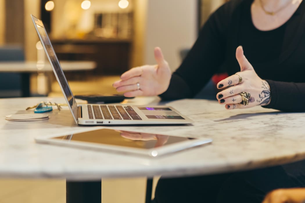 person gesturing near laptop