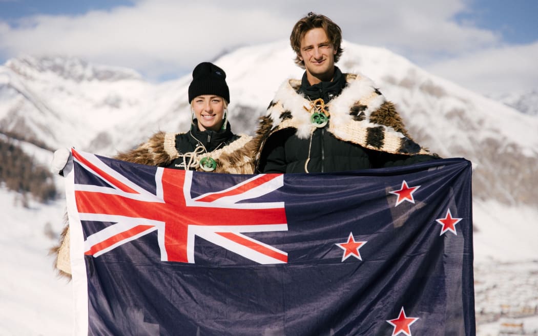 Snowboarder Zoi Sadowski-Synnott (L) and freeski athlete Ben Barclay (R) hold the NZ flag.