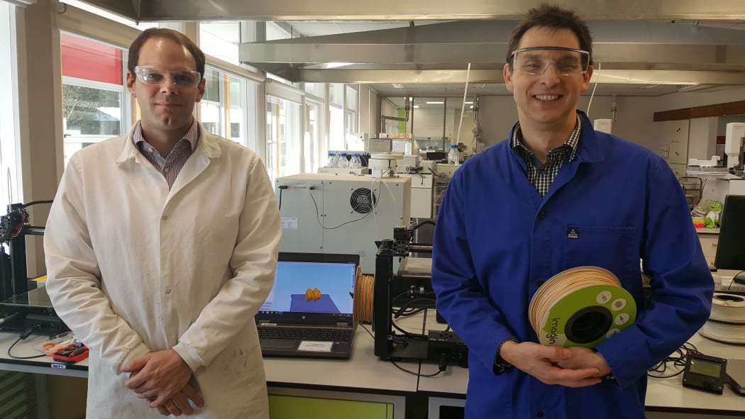 Marc Gaugler and Florian Graichen in front of 3D printing machines in the lab at Scion. Florian is holding a roll of wood-based bioplastic that can be used in the printers.