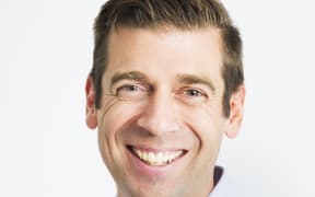 Dr Justin Coulson smiling in front of a white background