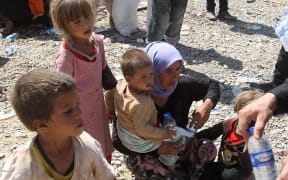 Peshmerga forces hand out water bottles to displaced Yizadi families from as they cross the Iraqi-Syrian border at the Fishkhabur crossing, in northern Iraq.