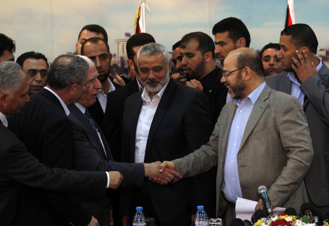 Fatah delegation chief Azzam al-Ahmed (centre left) and Hamas deputy leader Musa Abu Marzuk shake hands on the deal.