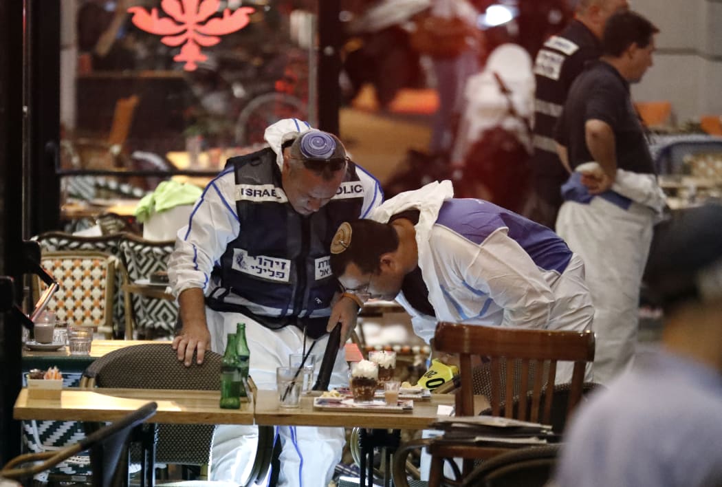 Israeli forensic police inspect a restaurant where gunmen opened fire, killing four people.