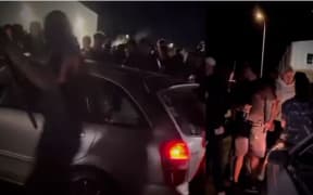 A screengrab from a video shows people swarming and attacking a car after a spectator was apparently struck during a boy racer car meet near Masterton early on Sunday morning.