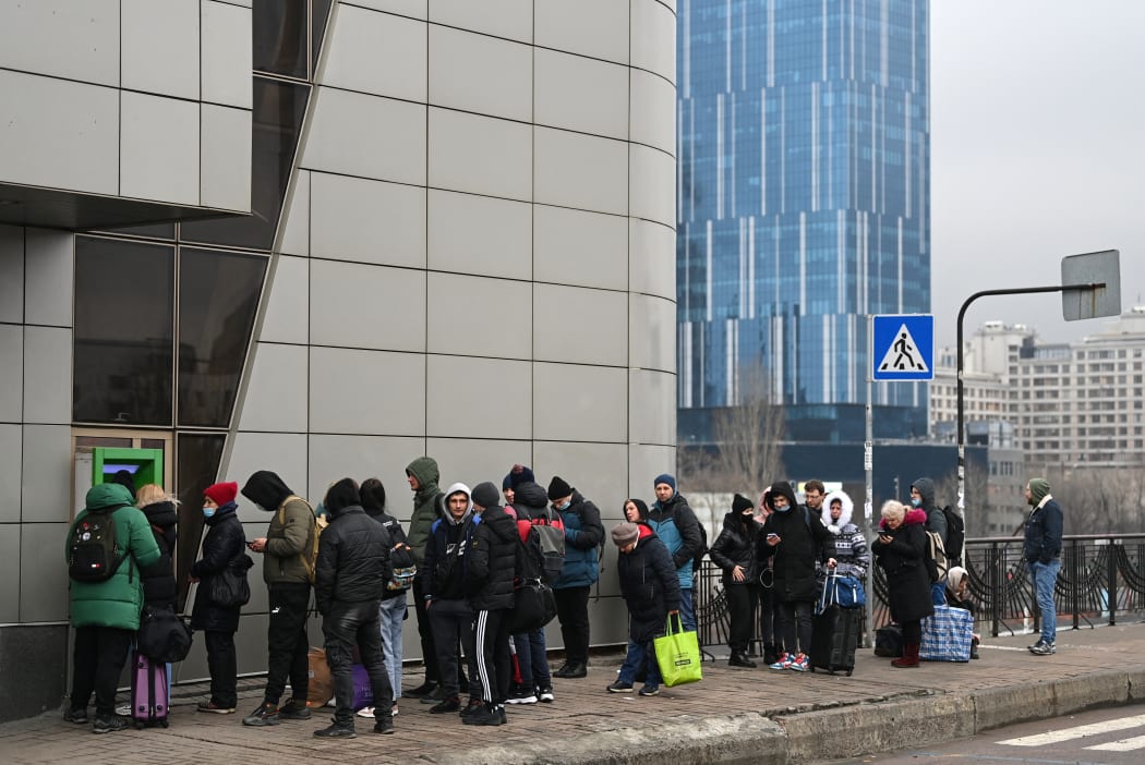 People line up to withdraw money at a cash dispenser in Kyiv in the morning of February 24, 2022.