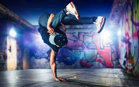 Young man break dancing at night on urban painted walls background