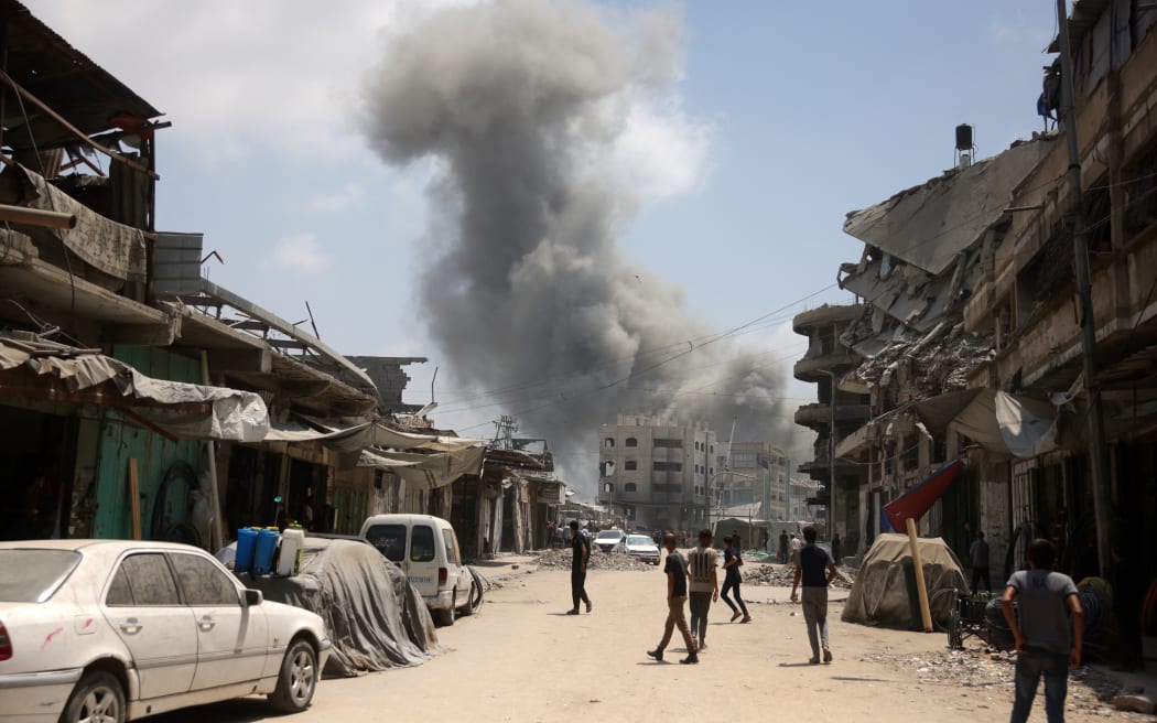 Palestinian watch as a plume of smoke rises during an Israeli strike on Gaza City's southern al-Zeitoun neighbourhood on August 8, 2025. Israel's military will "take control" of Gaza City under a new plan approved by Prime Minister Benjamin Netanyahu's security cabinet, touching off a wave of criticism Friday from both inside and outside the country. (Photo by BASHAR TALEB / AFP)