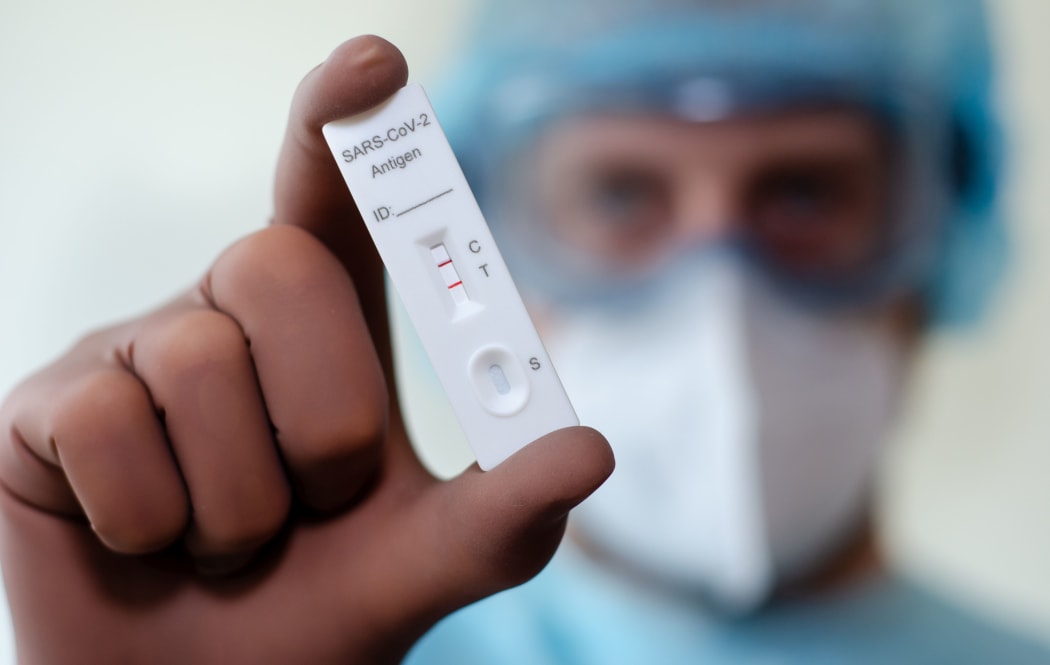 Medical laboratory assistant holding positive COVID-19 rapid test.