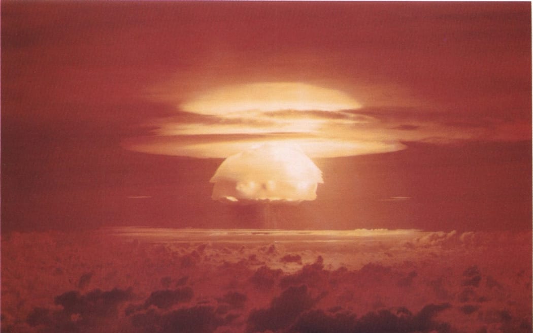 A large, fiery explosion creates a mushroom cloud against a dark red sky.