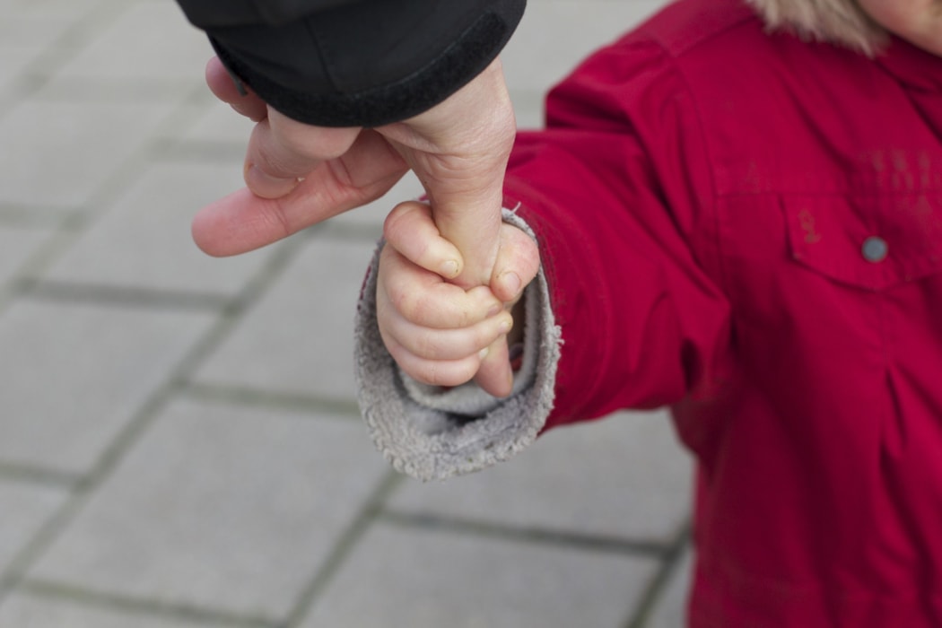 Child hand holding thumb