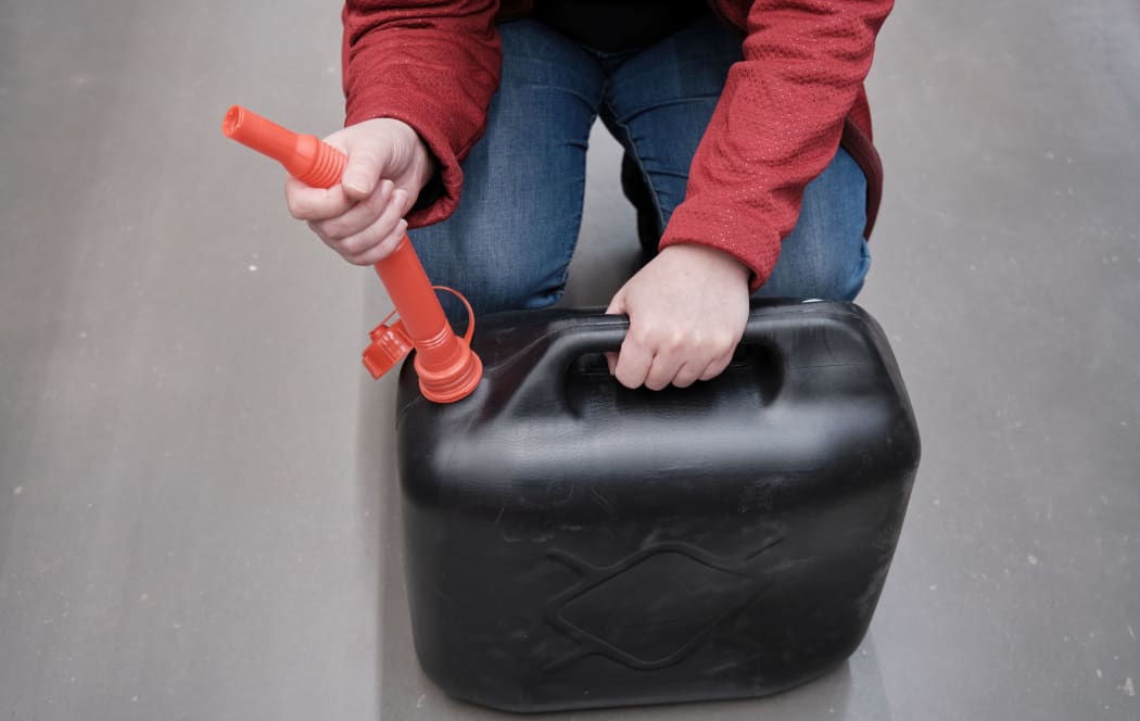 Woman in the parking lot store chooses for buys a canister with a flexible hose under fuel.