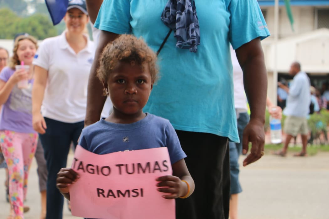 A boy hold a sign bearing the words "Thank you very much, RAMSI"