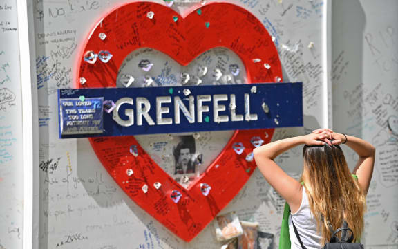 A woman reads messages of support written on the wall surrounding Grenfell Tower in west London on June 14, 2020, on the third anniversary of the high-rise fire that killed 72 people.