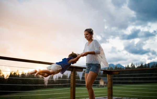 A woman in a park or farm spins around a toddler from their hands.