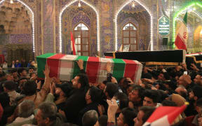 Mourners carry the coffins of slain Iraqi paramilitary chief Abu Mahdi al-Muhandis, Iranian military commander Qasem Soleimani and eight others inside the Shrine of Imam Hussein in the holy Iraqi city of Karbala during a funeral procession on 4 January.