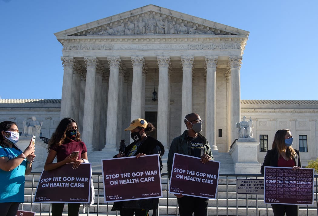 In this file photo taken on 10 November 2020 demonstrators hold signs in front of the US Supreme Court in Washington, DC, as the court opened arguments in the case over the constitutionality of the 2010 Affordable Care Act.