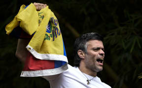 Leopoldo Lopez waves a Venezuelan flag on top of a wall outside his house in Caracas, hours after his release on Saturday 8 July 2017 (Venezuelan time).