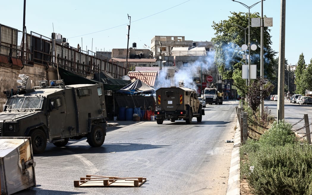 An Israeli military vehicle fires teargas during a raid on the Al-Amari refugee camp near Ramallah, in the occupied West Bank, on August 18, 2025. (Photo by Zain JAAFAR / AFP)