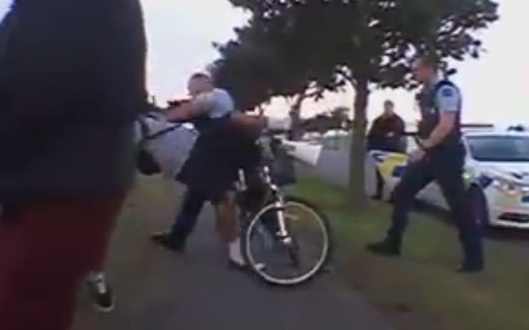 The Facebook video appears to show an officer push the young man off his bike onto the footpath.