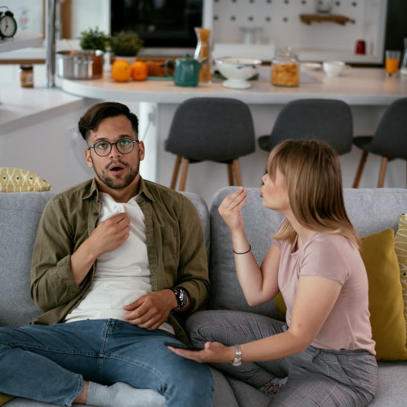 A young couple argue while sitting on a couch.