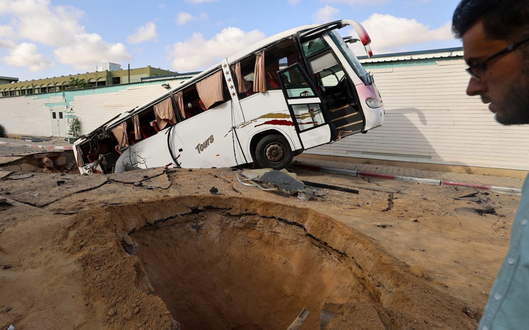 A man walks past a bus inside a crater in the aftermath of an Israeli strike in Khan Yunis in the southern Gaza Strip on 14 May 2025.