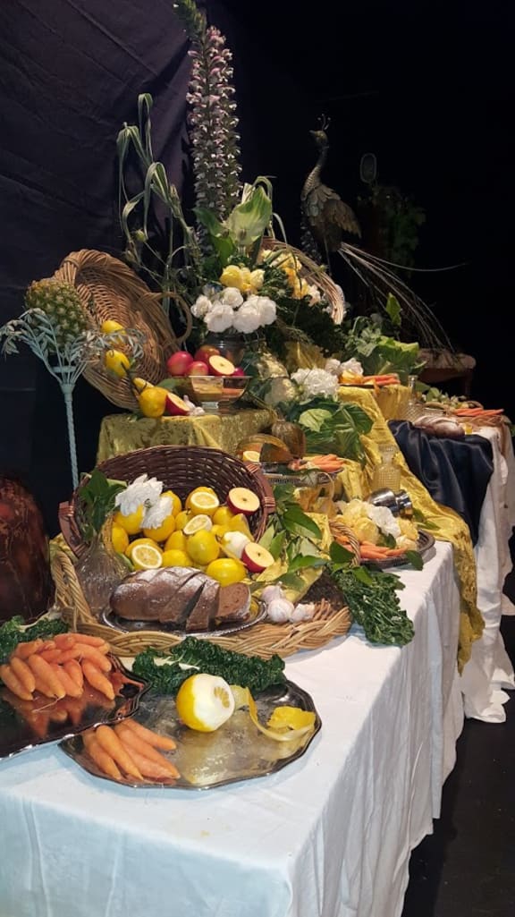 A still life display at the Symposium of Gastronomy, featuring fruits and vegetables arranged on a long, low table.