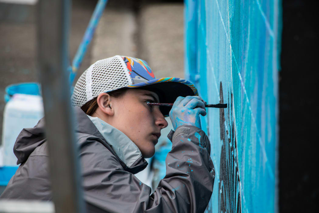 Twenty-year-old artist Noelle Anderson paints on Day 6.