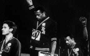 US athletes Tommie Smith, centre, and John Carlos, right, raise their gloved fists in the Black Power salute to express their opposition to racism in the US.