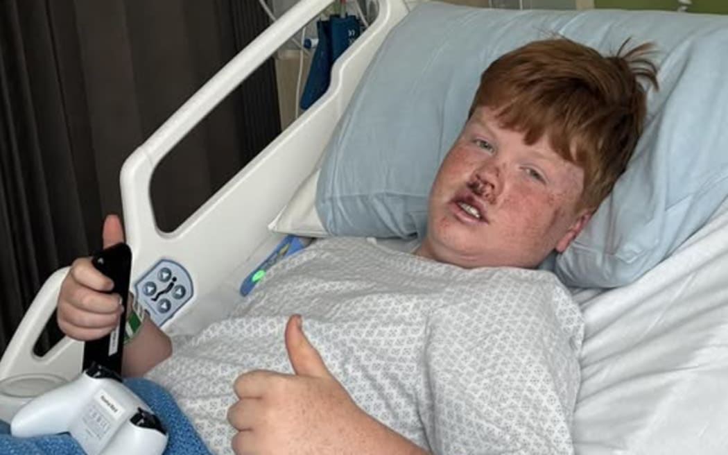 Dominic Gardner in hospital gives two thumbs up.