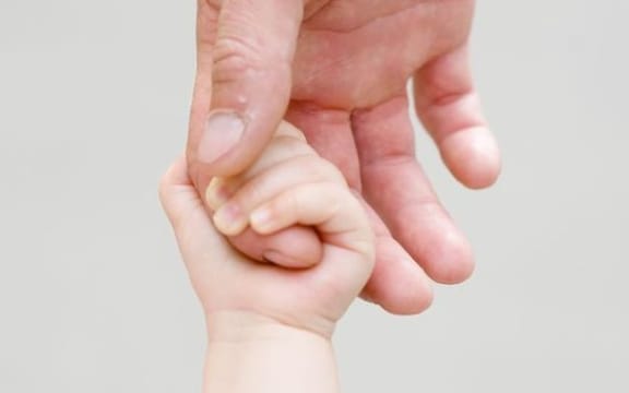 A close up of a child holding and adult's hand