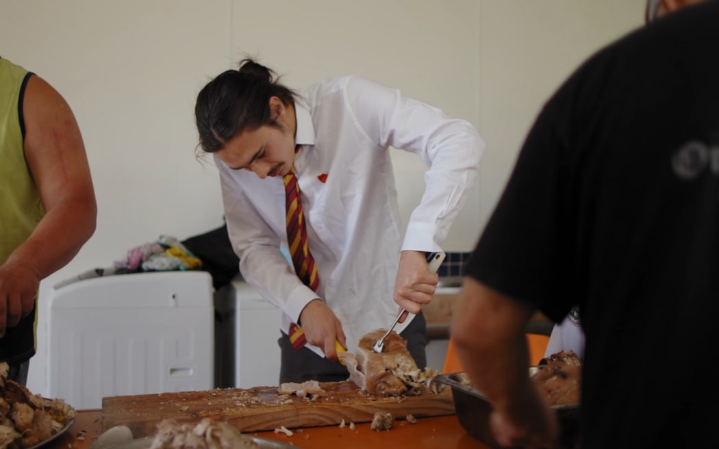 Uenuku in wharekai cutting meat for 21st