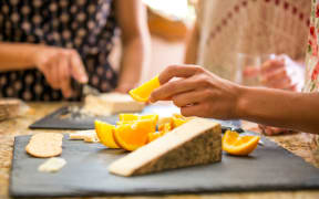 Close up of three adult sisters snacking from cheese board (Photo by Deborah Kolb / Image Source / Image Source via AFP)