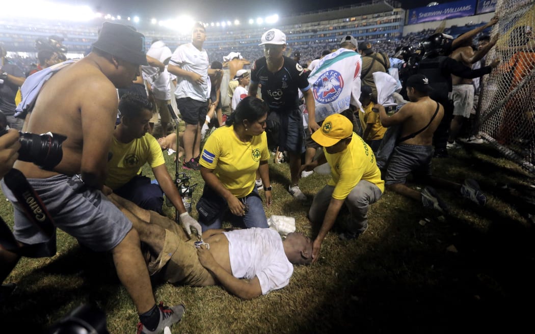 Rescuers attend an injured man lying on the pitch following a stampede during a football match between Alianza and FAS at Cuscatlán stadium in San Salvador on 20 May, 2023, which killed at least nine people.