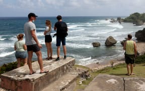 Tourists look on at the rock formations along the coast on November 18, 2021 in Cattle Wash, Barbados.