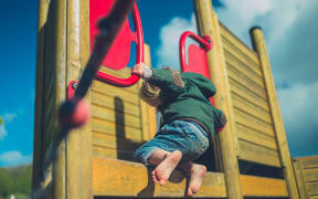 A toddler climbing in a playground.