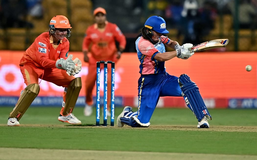 Amelia Kerr of Mumbai Indians (R) plays a shot during the Women's Premier League (WPL) Twenty20 cricket match between Mumbai Indians and Gujarat Giants at the Chinnaswamy Stadium in Bengaluru on February 25, 2024. (Photo by Idrees MOHAMMED / AFP)