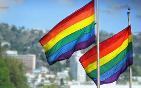 21543261 - a pair of rainbow flags waving in wind against city background of west hollywood, california