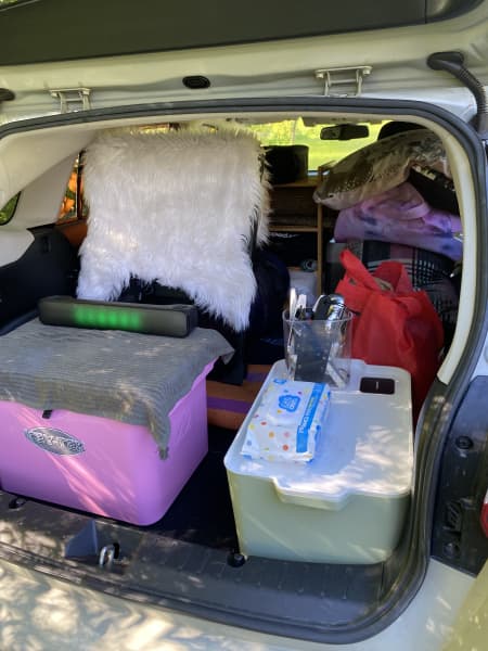 Car boot open showing container boxes and soft bags in the back.