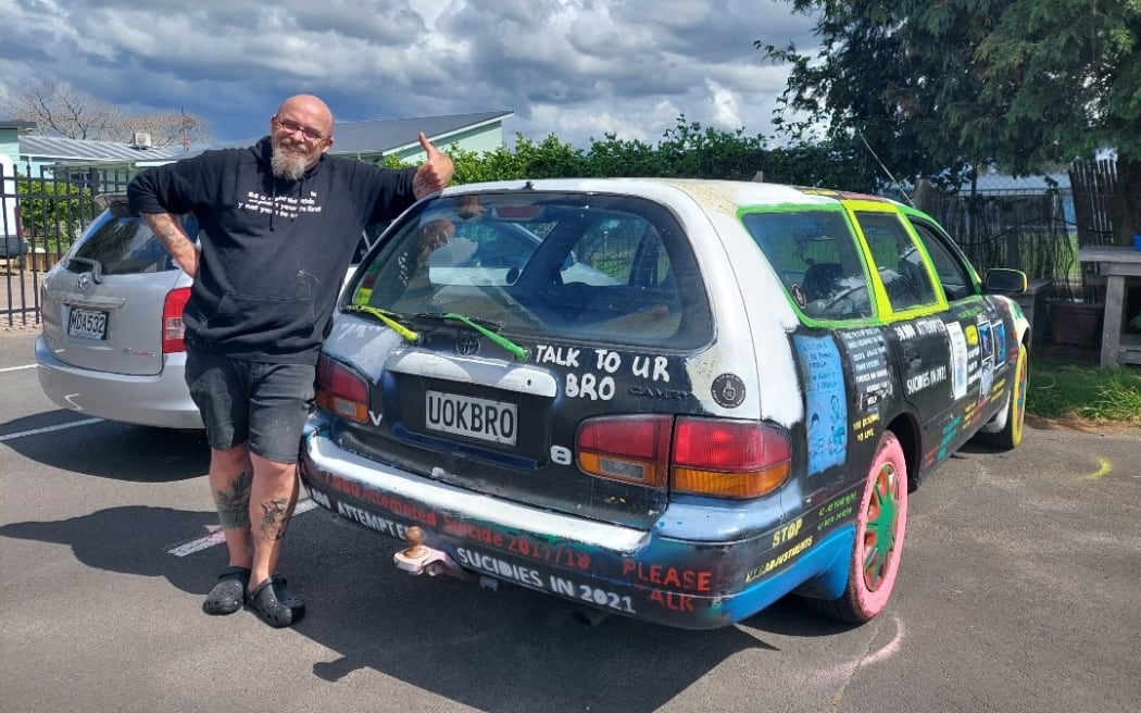 Social worker Scotty Harvey stands in front of his 1997 Toyota Camry which is covered from bonnet to boot in messages. His number plate says UOKRBO
