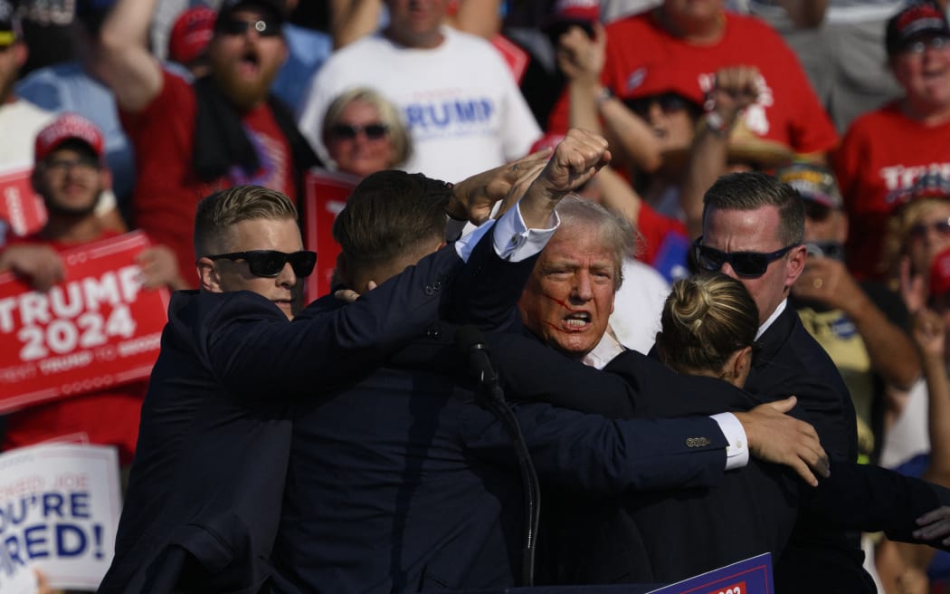 BUTLER, PENNSYLVANIA - JULY 13: Republican presidential candidate, former U.S. President Donald Trump is whisked away by Secret Service after shots rang out at a campaign rally at Butler Farm Show Inc. on July 13, 2024 in Butler, Pennsylvania. Trump slumped and injuries were visible to the side of his head. Butler County district attorney Richard Goldinger said the shooter and one audience member are dead and another was injured.   Jeff Swensen/Getty Images/AFP (Photo by JEFF SWENSEN / GETTY IMAGES NORTH AMERICA / Getty Images via AFP)