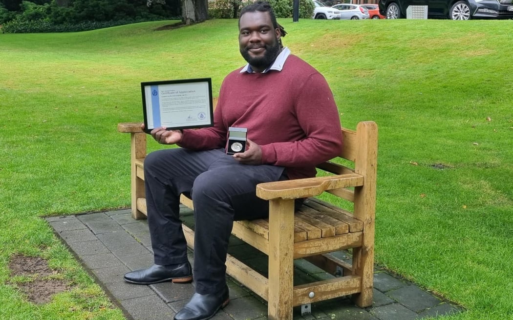 Samson Aruwa on the seat dedicated to Sophia Crestani in Dunedin