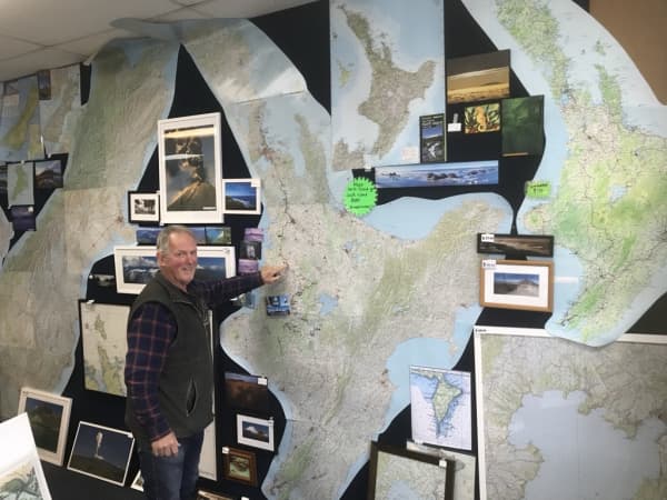 Owner of the Map and Chart shop, one of the few remaining specialist map shops in the country, Murray Jones pointing at a New Zealand map on the wall of his shop.