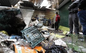 Iraqis look at the aftermath following a double blast in a busy market area in Baghdad's central al-Sinek neighbourhood on 31 December , 2016.