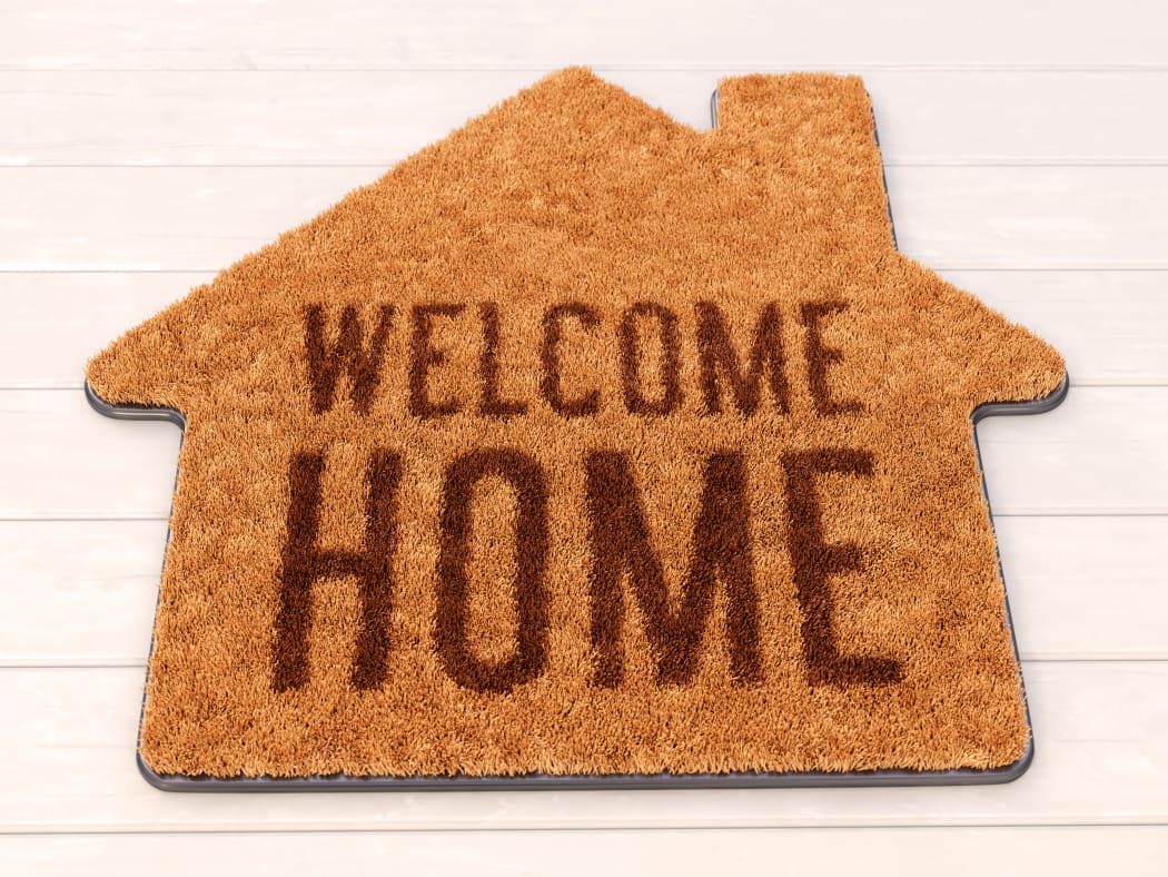 Brown house icon shape coir doormat with text print Welcome Home on wooden floor. 3D illustration
